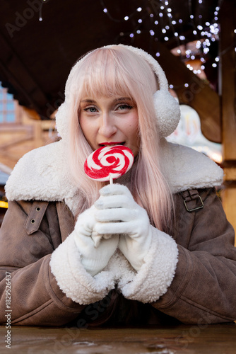 Girl eating lollipop. Festive Winter Portrait at Christmas Market