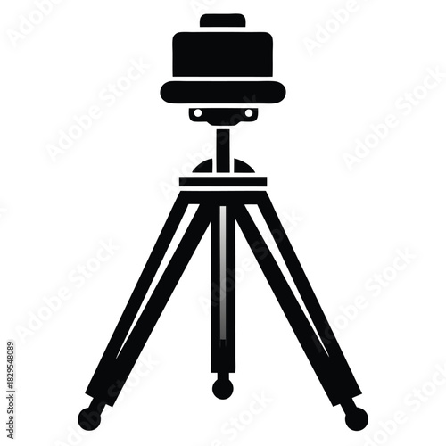 A black photography tripod is standing upright on a white surface for steady shooting
