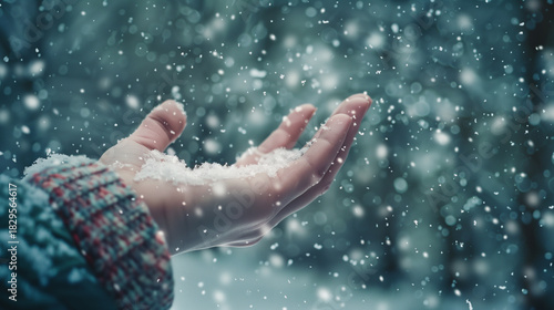 Hand catching snowflakes while snowing in winter forest  