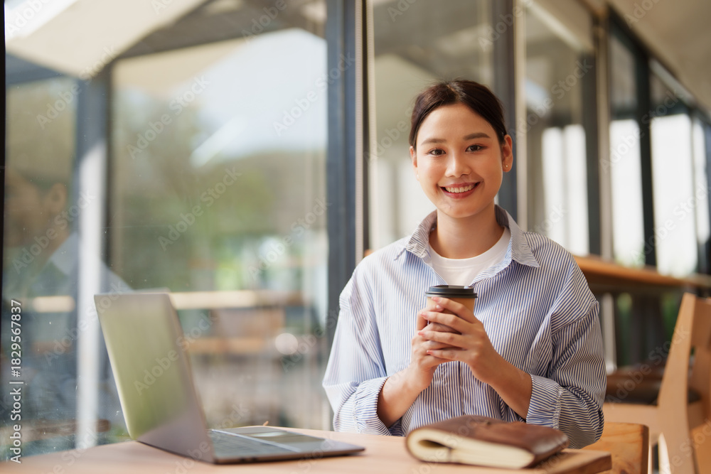 Obraz premium Young woman enjoying coffee while working remotely at cafe
