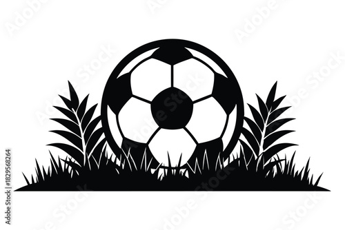 A silhouette reveals a soccer ball partially hidden within lush, wild grass and foliage