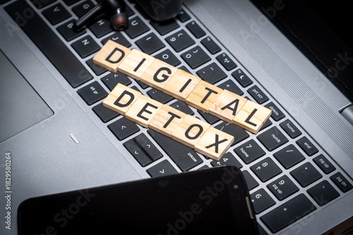Flat lay composition featuring a Digital Detox sign surrounded by a smartphone, headphones, and laptop. Concept of unplugging, reducing screen time, and mental health awareness
