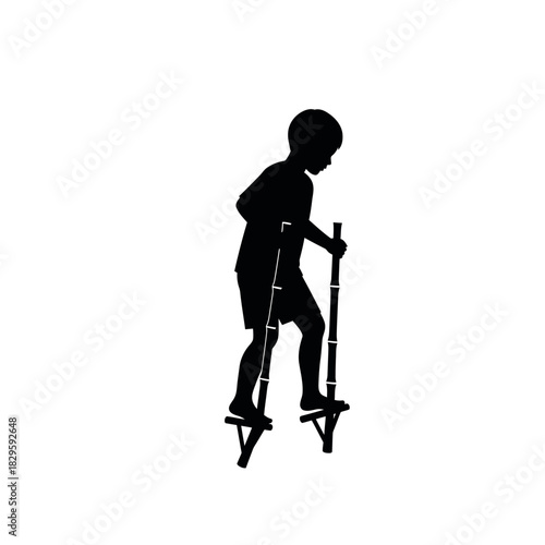 Silhouette of a young boy walking on stilts.