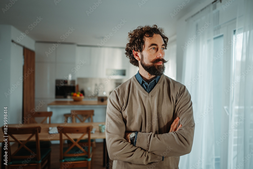 Fototapeta premium Thoughtful man with beard and mustache contemplating at home