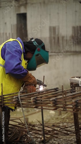 Vertical close up slow motion of construction worker welding rebar on building site