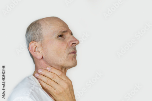 Bold senior man is holding his throat. Cold or thyroid gland health concept