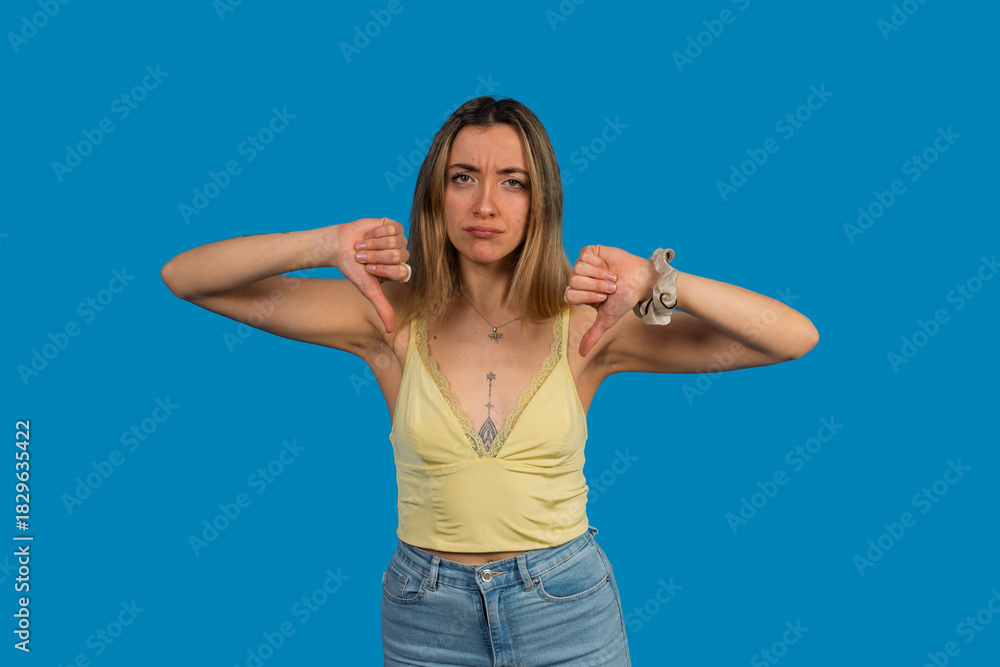 Fototapeta premium Woman expressing dislike with thumbs down gesture