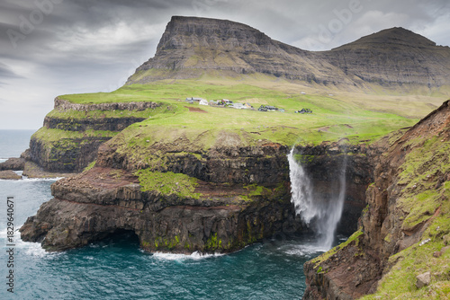 waterfall with the village Gasadalur in background on faroe islands