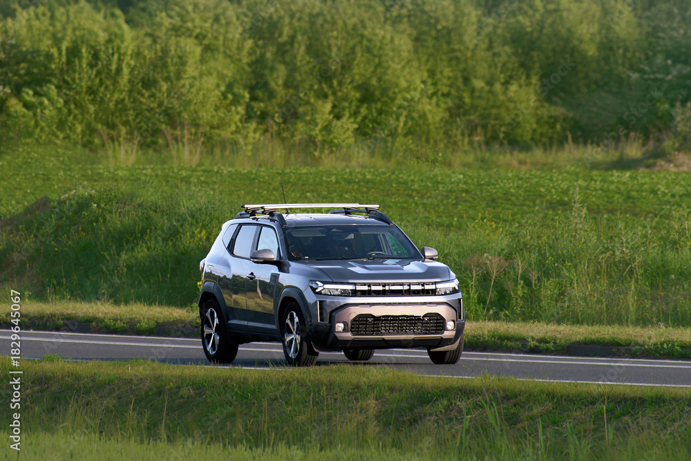 Fototapeta premium Compact city SUV traveling across green farmland