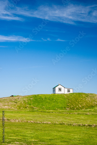 little house in iceland between a grenn meadow and the blue sky