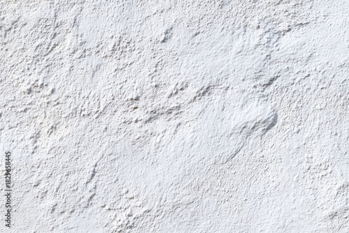 Textured Plaster: A close-up view reveals a rough, tactile, plaster wall surface with irregular patterns, offering a minimalist aesthetic, presenting a rich display of shadows and textures.