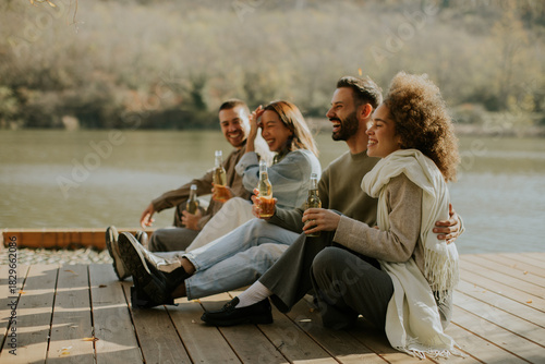 Friends enjoying a peaceful afternoon by the river, sharing laughter and drinks together