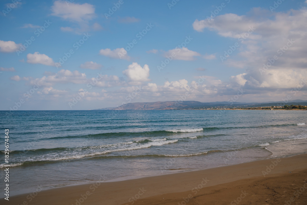 Fototapeta premium Vibrant seascape: deep azure waters under a clear sky with scattered white clouds