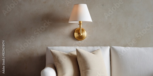 Cozy wall sconce, above a neutral couch with soft, inviting pillows