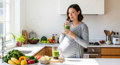 Pregnant woman enjoying a healthy green smoothie in a bright kitchen full of fresh vegetables and fruits