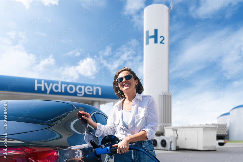 Fototapeta premium Woman holds a hydrogen fueling nozzle on a hydrogen filling station. Refueling car with hydrogen fuel