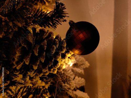 Glass Christmas bauble or ornament hanging on a flocked artificial Christmas tree branch