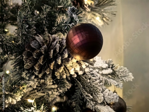 Glass Christmas bauble or ornament hanging on a flocked artificial Christmas tree branch