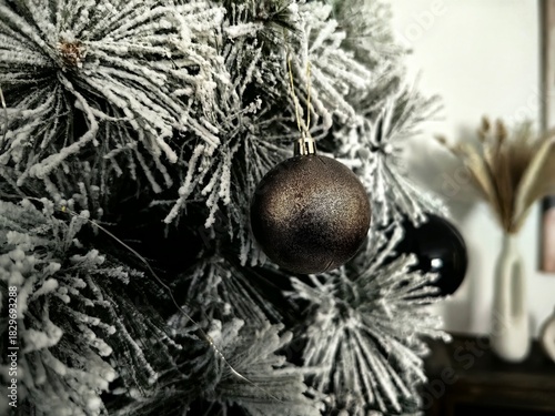 Glass Christmas bauble or ornament hanging on a flocked artificial Christmas tree branch