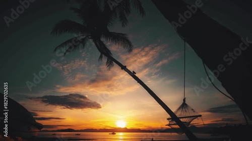 Tranquil tropical sunset over the ocean with silhouette palm trees and a hanging hammock inviting relaxation by the serene coastline