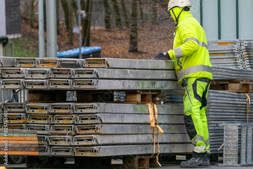 Construction Worker Stacking Metal Scaffolding Decks Hi Vis Gear Site Logistics