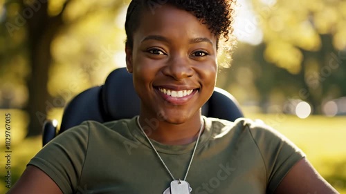 smiling african american woman veteran in wheelchair wearing dog tags in sunny park. disabled military female portrait. diversity and inclusion concept.