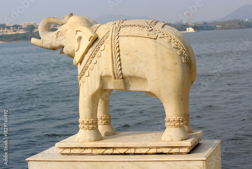 Huge white elephant statue standing next to a lake in Asia