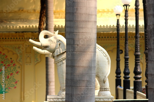 White marble elephant statue behind coconut tree