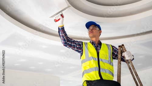 Construction worker applying finishing touches to ceiling interior renovation modern workspace elevated view professional skill application