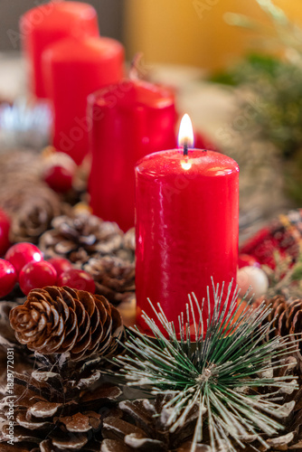 Red candles surrounded by pine cones and holiday decorations create a warm atmosphere during the festive season