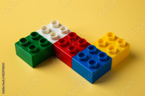 Colorful toy blocks building creativity on yellow background