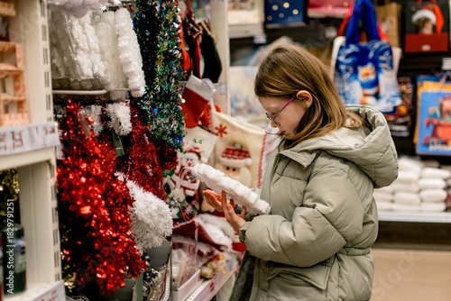 A girl in a store among Christmas decorations. Preparing for the New Year and Christmas. Buying decorations and gifts.