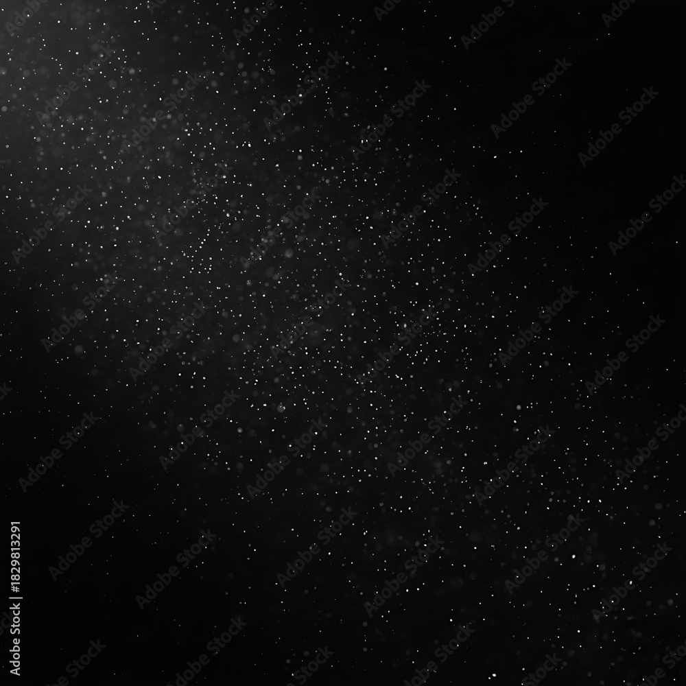 Fototapeta premium Tiny, bright white dust motes suspended in darkness, catching a soft, ethereal light from an unseen source.