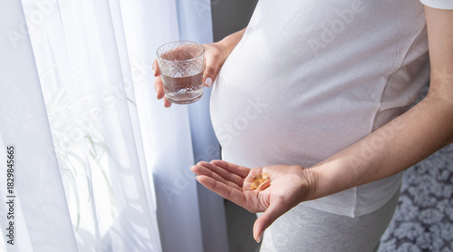 A pregnant woman drinks vitamins and supplements. Selective focus.