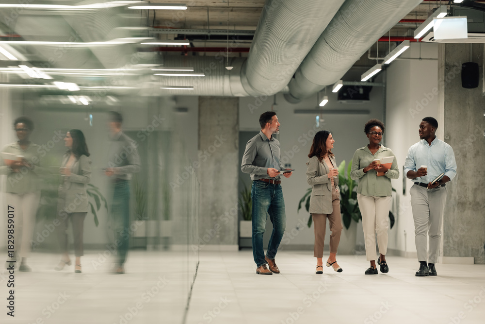 Fototapeta premium Diverse business team walking through modern office discussing work