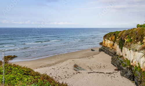 Empty sand cove with sedimentary rock cliffs on the Atlantic coast of Northern Spain.