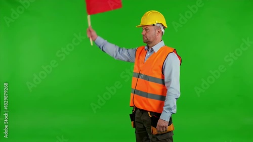 Construction Worker Directing Traffic with a Red Flag on Green Screen.