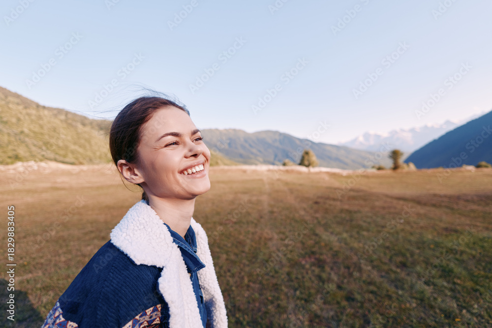Fototapeta premium Woman smile portrait mountains meadow nature outdoor happiness captured in candid closeup of young female wearing fleece jacket at sunrise in scenic valley landscape enjoying freedom.