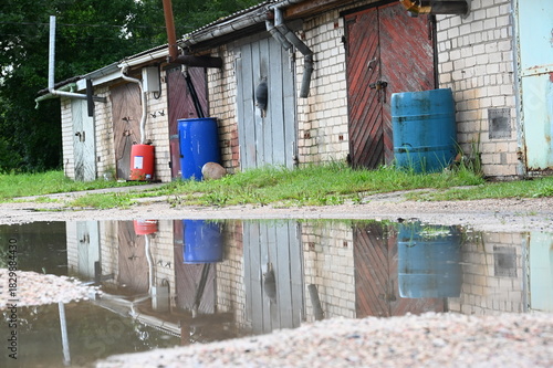 Lettland: Eine Reihe rustikaler Garagen spiegelt sich in einer Wasserpfütze