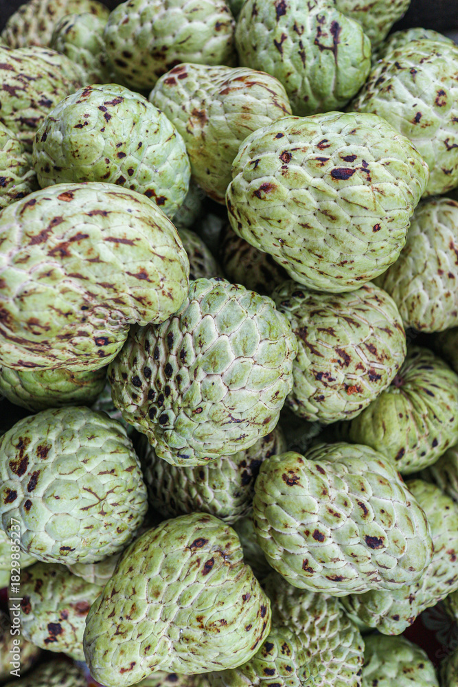 Obraz premium Organic custard apples arranged in a textured overhead pattern, creating a tropical background that highlights natural food aesthetics, healthy eating, and sustainable agriculture.