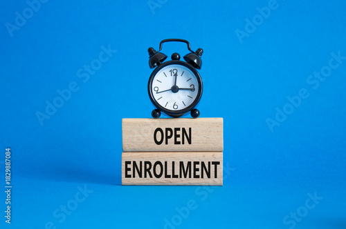 Open Enrollment symbol. Wooden blocks with words Open Enrollment. Beautiful blue background with alarm clock. Business and Open Enrollment concept. Copy space.
