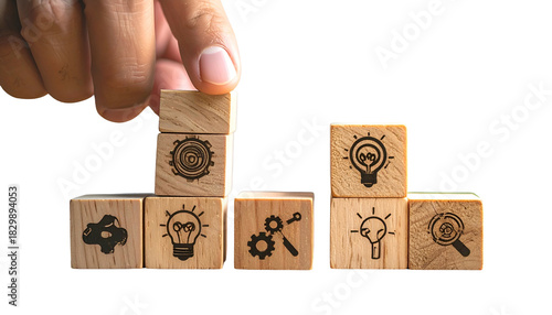 Hand building a tower of wooden blocks with etched business concept symbols