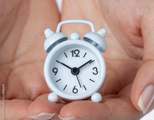 Tiny alarm clock held between two hands, symbolizing the preciousness of time and the importance of managing it wisely