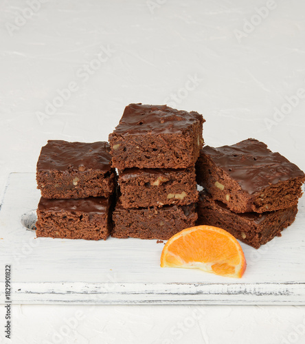 Stack of square baked slices of brownie chocolate cake with walnuts