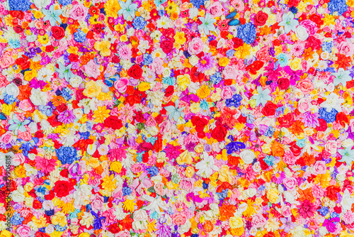Foto カラフルな造花が密集した華やかな花壁のクローズアップ背景／Close-up background of a vibrant artificial flower