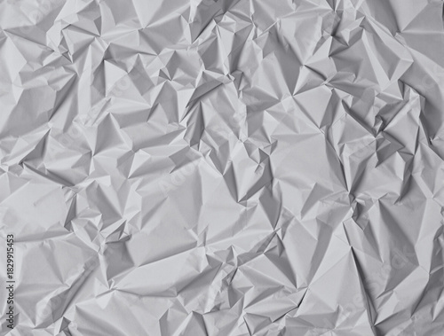 Abstract textured background of a crumpled white paper sheet, revealing a complex geometric pattern of sharp folds and creases under dramatic lighting