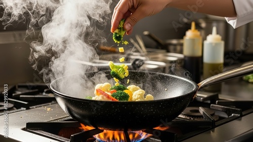 Chef cooking stir fry vegetables in a wok on a gas stove in a professional kitchen food preparation