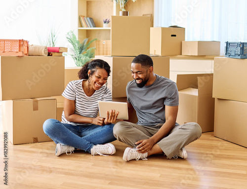 Portrait of a young couple unpacking, moving in and relocation to a new apartment, happy young couple  using a tablet, browsing and shopping online, , family new beginning sitting on the floor