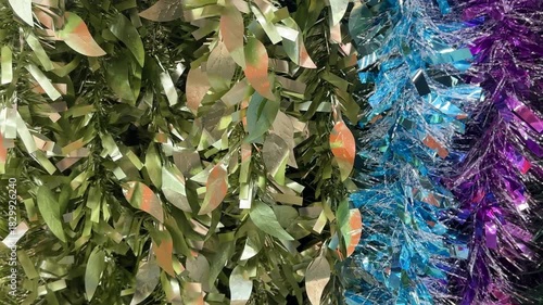 Close up background texture of christmas tinsels garland in holographic pink colors. Made of glossy materials, tinsels are used to decorate christmas tree or rooms in festivity. Merry Christmas