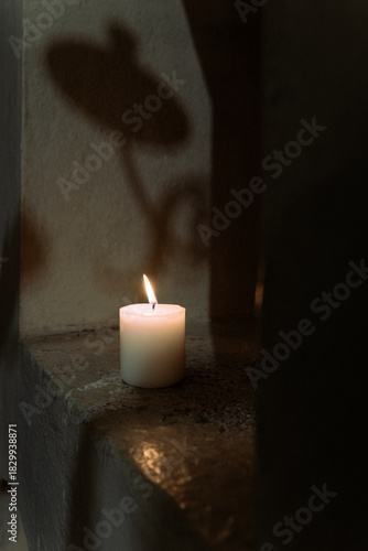 Single Burning Candle Casting Soft Shadows on Stone Surface in Peaceful Low Light